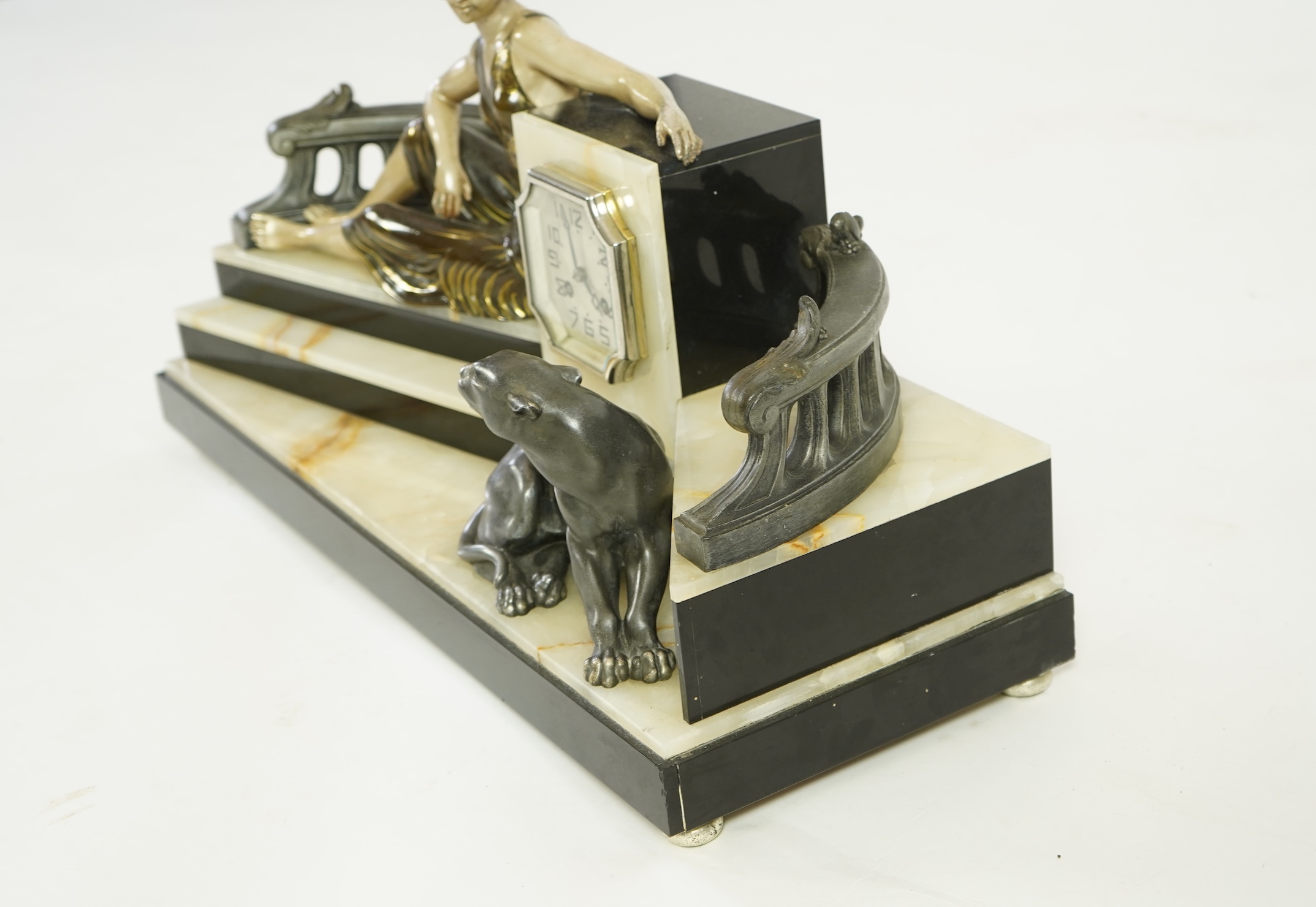 A French Art Deco onyx and patinated spelter clock surmounted with a lady and a black panther on a staircase